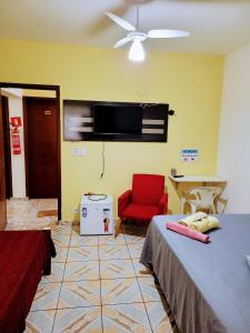 a bedroom with a bed and a chair and a flat screen tv at Hospedaria São Benedito in Guararema