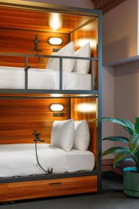 a four bunk bed room with white pillows and a plant at Roamer St Kilda - formerly Selina St Kilda Melbourne in Melbourne