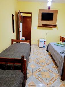 a room with two beds and a flat screen tv at Hospedaria São Benedito in Guararema