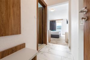 a bathroom with a mirror and a white tile floor at Hotel Villa Barbara in Neum