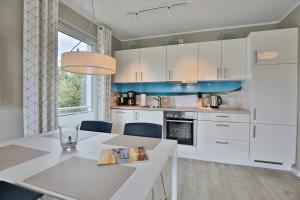 una cocina con armarios blancos y una mesa con sillas. en Strandglück Haus C Strandglück Appartement Strand 6, en Scharbeutz