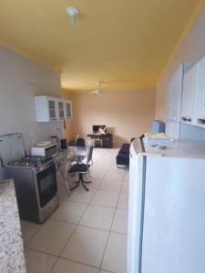 Una cocina con suelo de baldosas blancas y un refrigerador. en Casa com piscina , churrasqueira, Wi-Fi, em rua de Areia à 1km da praia, bairro sussegado, proíbido uso de som extremamente alto ideal para descansar, en Itanhaém