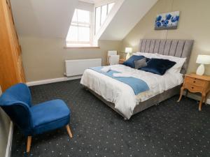 a bedroom with a bed and a blue chair at Heanor House in Leyburn