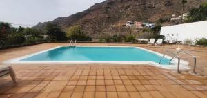 a large swimming pool with a mountain in the background at Apartamento El Cercado Mogan in Mogán