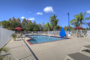 a swimming pool with chairs and umbrellas on a patio at Motel 6-Orlando, FL - International Dr in Orlando