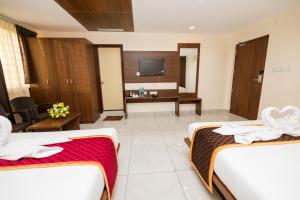 a hotel room with two beds and a television at KK Comforts in Shrīrangapattana