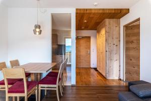 comedor y cocina con mesa de madera y sillas en Hohenegg Apartment Julian en Sarntal