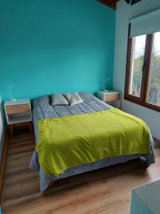 um quarto azul com uma cama com um cobertor amarelo em Cálida casa en el fin del mundo em Ushuaia