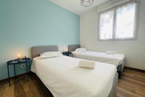 two beds in a room with two windows at Spacious modern house near the Golf of Ardrée in Saint-Antoine-du-Rocher