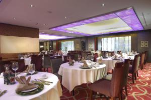 una sala da pranzo con tavoli e sedie bianchi di Metropark Hotel Kowloon a Hong Kong