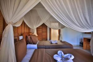 two beds in a bedroom with white curtains at Bintang Bungalow in Nusa Penida