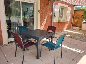 la Villa rouge Ardèche "le Baya" في Ucel: طاولة سوداء حولها أربعة كراسي +صورتان