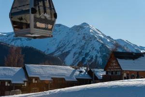 une remontée mécanique survolant une montagne enneigée dans l'établissement Chalet Hôtel Les Blancs, à Pra-Loup