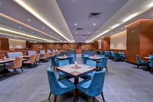a dining room with tables and blue chairs at Hotel Tip Top International Pune in Pune