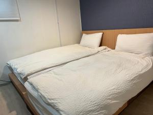 a large bed with white sheets and pillows at Chris Hostel in Seoul