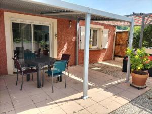 een patio met een tafel en stoelen in een huis bij maison zen 60m2 proche Aubenas le Baya in Ucel