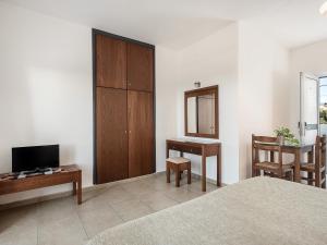 Dormitorio con cama, escritorio y TV en Nontas suites en Kato Daratso