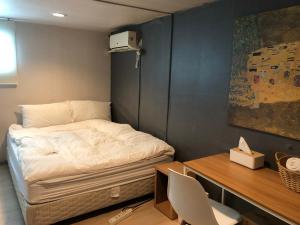 Habitación pequeña con cama, escritorio y escritorio. en Chris Hostel, en Seúl