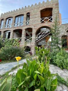 un antiguo edificio de ladrillo con ventanas y plantas en Guest House Lali, en Signagi