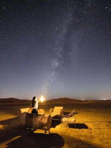 a woman sitting on a plane in the desert at night at Merzouga Paradise Luxury Camp in Merzouga