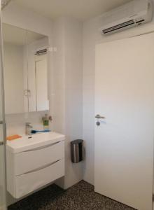 uma cozinha branca com um lavatório e um espelho em Apartman Sara em Umag