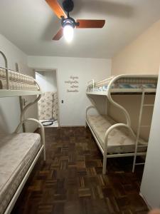 a room with two bunk beds and a ceiling fan at Apt com vista para o mar e churrasqueira in Guaratuba