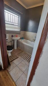 a bathroom with a tub and a toilet and a sink at Epic Den Lodge in Phuthaditjhaba