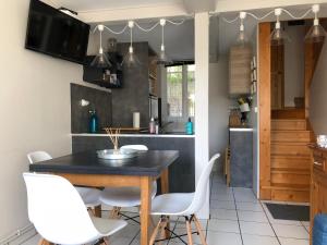 une cuisine avec une table noire et des chaises blanches dans l'établissement La courtine Etretat maison de pêcheur 2 mn de la mer, à Étretat