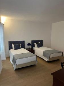 a bedroom with two beds and a table with a lamp at O Conventinho in Évora