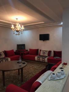 ein Wohnzimmer mit roten Sofas und einem Tisch in der Unterkunft اقامة السعادة in Nador