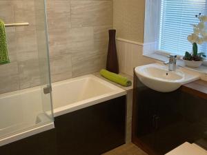 a bathroom with a sink and a bath tub at Sleepy Fox Cottage in Levisham