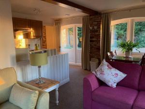 a living room with a purple couch and a kitchen at Sleepy Fox Cottage in Levisham