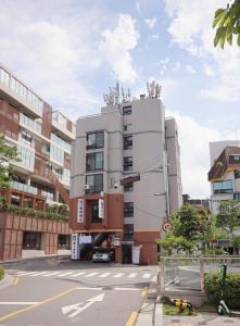 un edificio blanco alto en una calle de la ciudad en LikeU Guest house, en Seúl