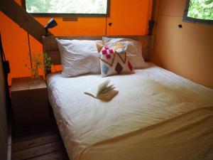 a bed with a pink blanket and pillows on it at Camping Barco Reale in Lamporecchio