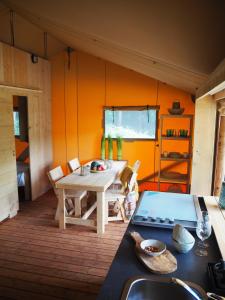 Habitación con mesa y cocina con paredes de color naranja. en Camping Barco Reale, en Lamporecchio