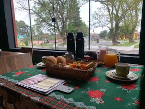 a table with a basket of bread and orange juice at Central Chalés in Cambará