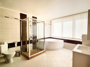 La salle de bains est pourvue d'une douche, d'une baignoire et de toilettes. dans l'établissement Парк Апарт-Хотел Виктория 1, à Sandanski