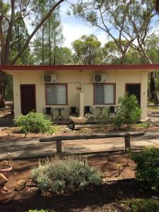 une petite maison avec un banc devant elle dans l'établissement Wagon Wheel Motel & Units, à Coonabarabran