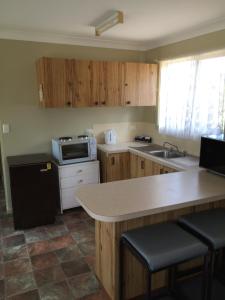 a kitchen with wooden cabinets and a sink and a microwave at Wagon Wheel Motel & Units in Coonabarabran