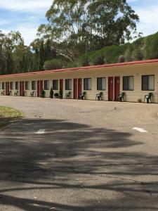 a building with red doors and benches in a parking lot at Wagon Wheel Motel & Units in Coonabarabran