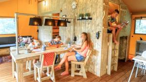 a woman sitting on a wooden chair in a kitchen at Camping Barco Reale in Lamporecchio