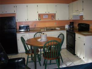 a kitchen with a table and chairs and a kitchen with white cabinets at All-Suite Motel, LLC in Edgewater