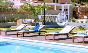 a pool with three lounge chairs and an umbrella at Stavento Luxury Villa Private Pool in Georgioupolis
