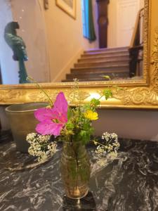 een vaas met bloemen op een tafel voor een spiegel bij Maison De l'Aguze in Saint-Pons