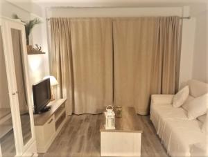a living room with a white couch and a television at FUENGIROLA PLAYA y PISCINA PERLA 2 ESTUDIO in Fuengirola