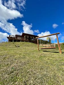 a swing on a hill in front of a house at Cabana Dois Amores. Destino romântico. in Barracão