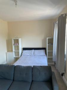 a bedroom with a bed and a blue couch at Private Rooms In A Cheerful 4-Bedroom Town House in Broughton