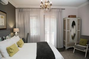 a bedroom with a large white bed and a chandelier at 5 Konings Guesthouse in Paarl
