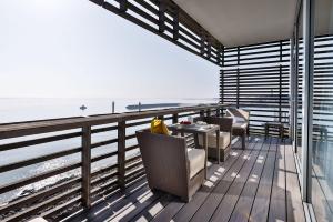 uma varanda com cadeiras e uma mesa na praia em BUDERSAND Hotel - Golf & Spa - Sylt em Hörnum