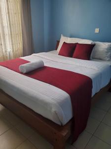 um quarto com uma cama grande e almofadas vermelhas em MAMU'S RESIDENCE near JKIA em Nairobi